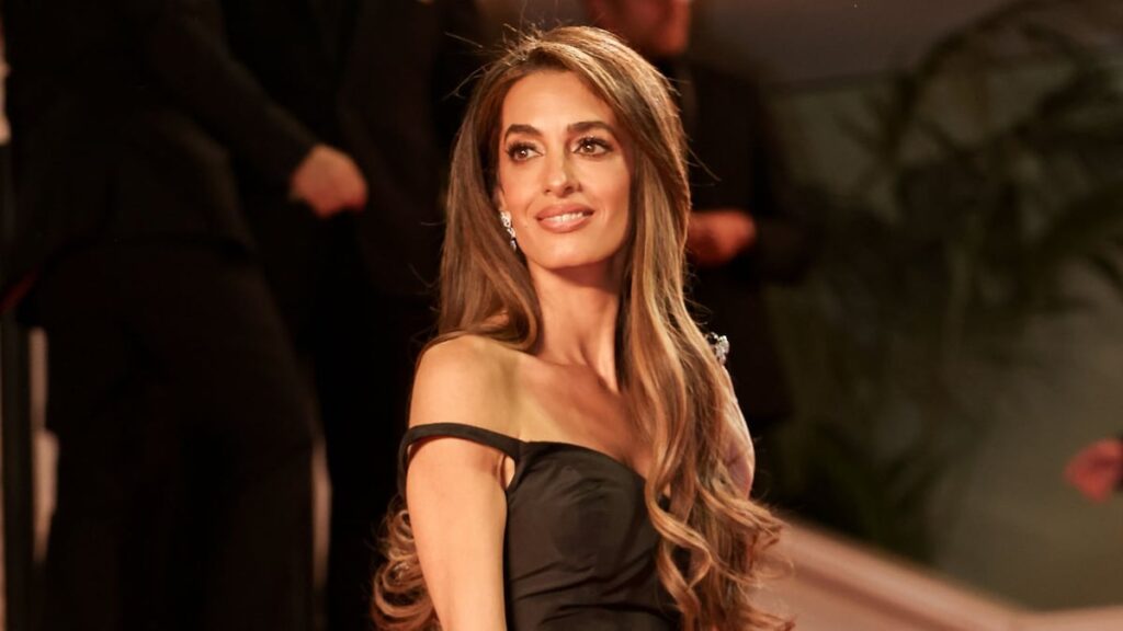 Amal Clooney es una diosa con bata de hendidura blanca y plateada en Londres