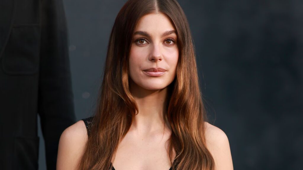 Camila Morrone llama la atención con un top corto blanco y una falda de seda antes de posar con un look de encaje transparente en el estreno de Los Ángeles.
